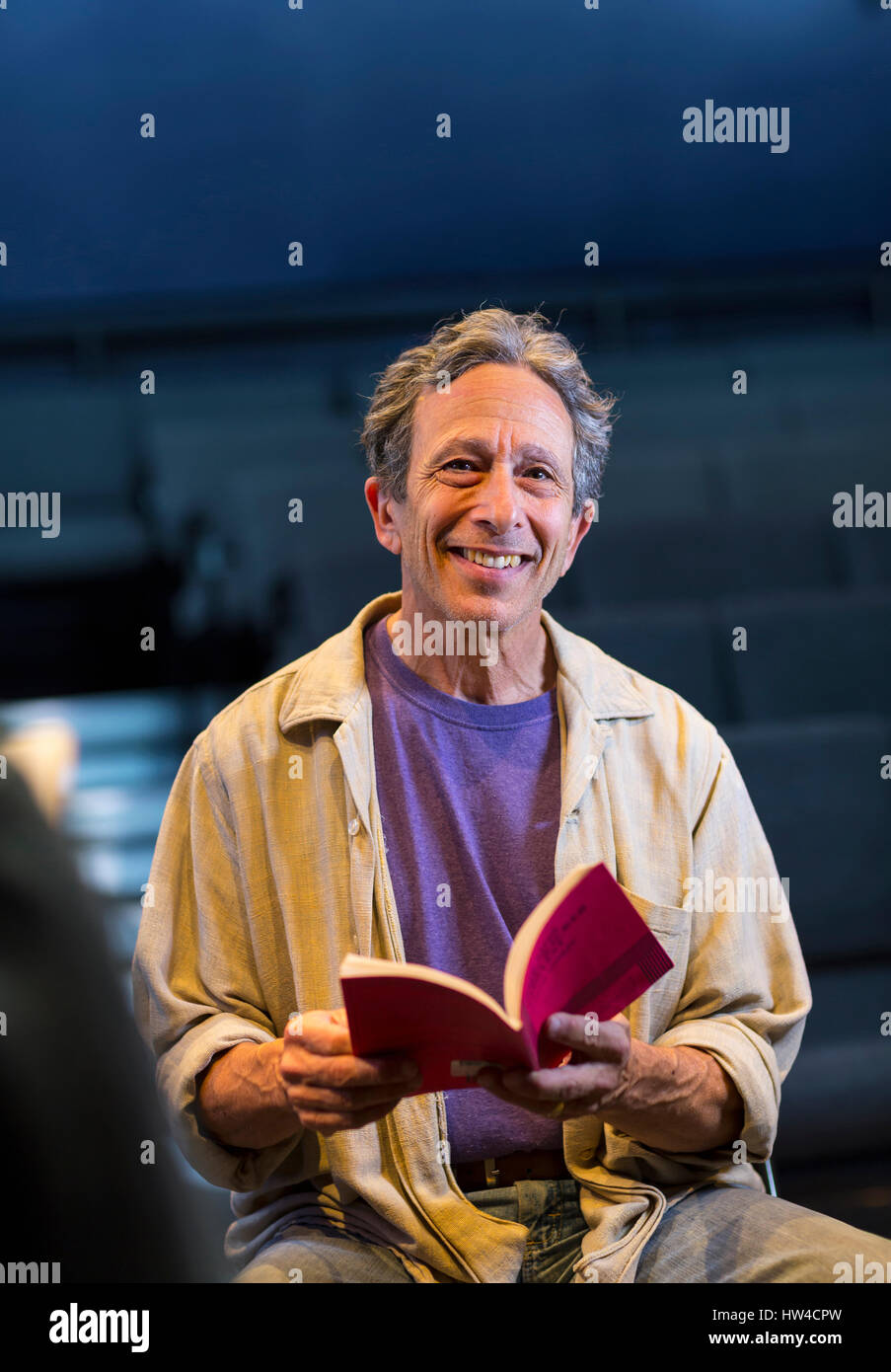 Portrait of smiling Caucasian actor holding script in theater Stock Photo