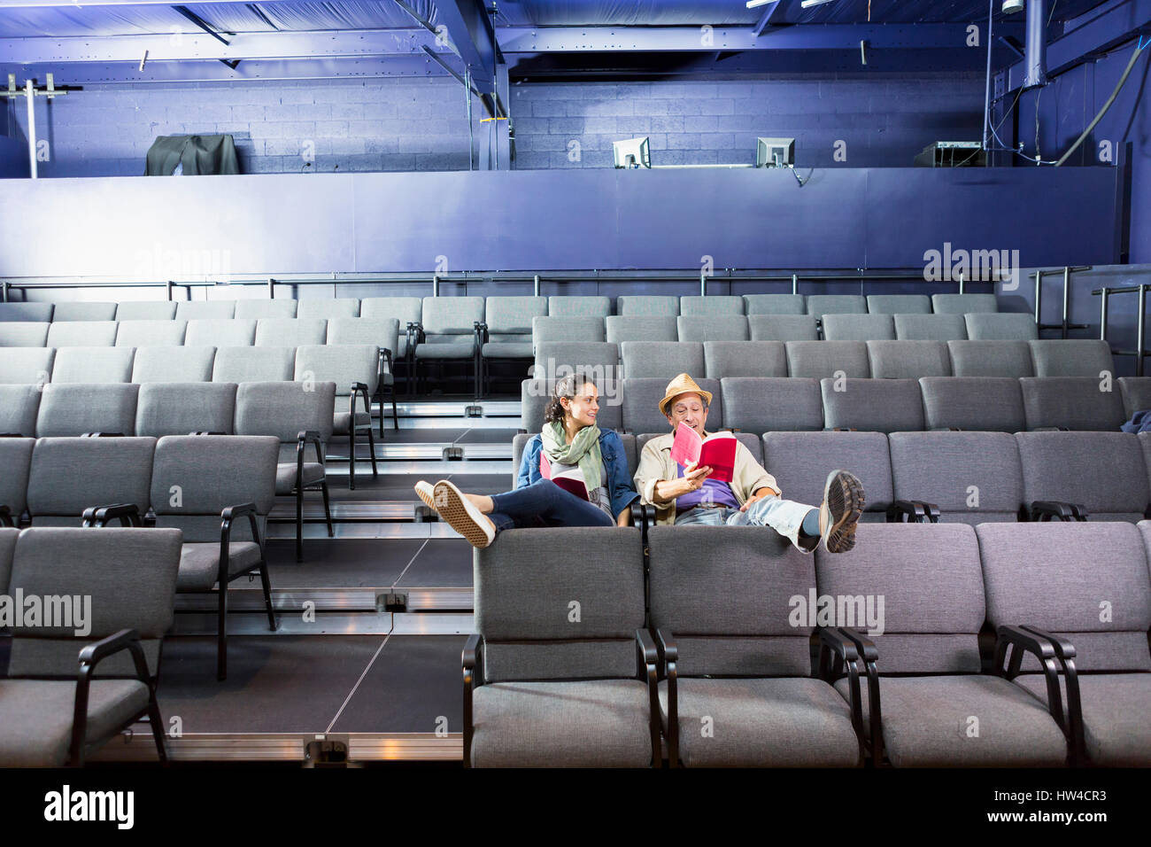 Caucasian actors sitting in audience with scripts in theater Stock
