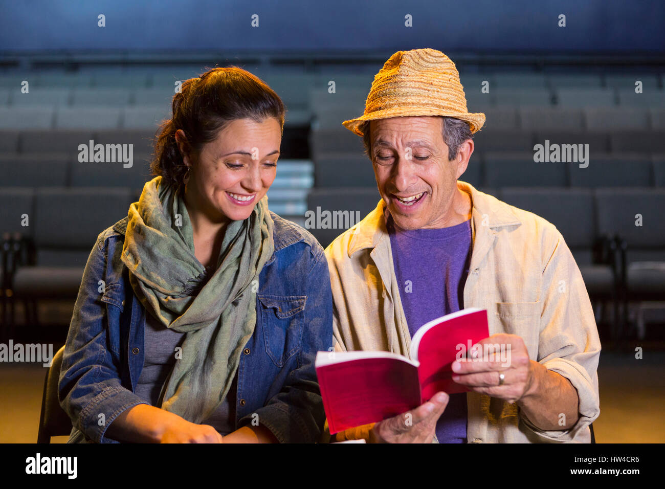 Caucasian actors rehearsing with script in theater Stock Photo