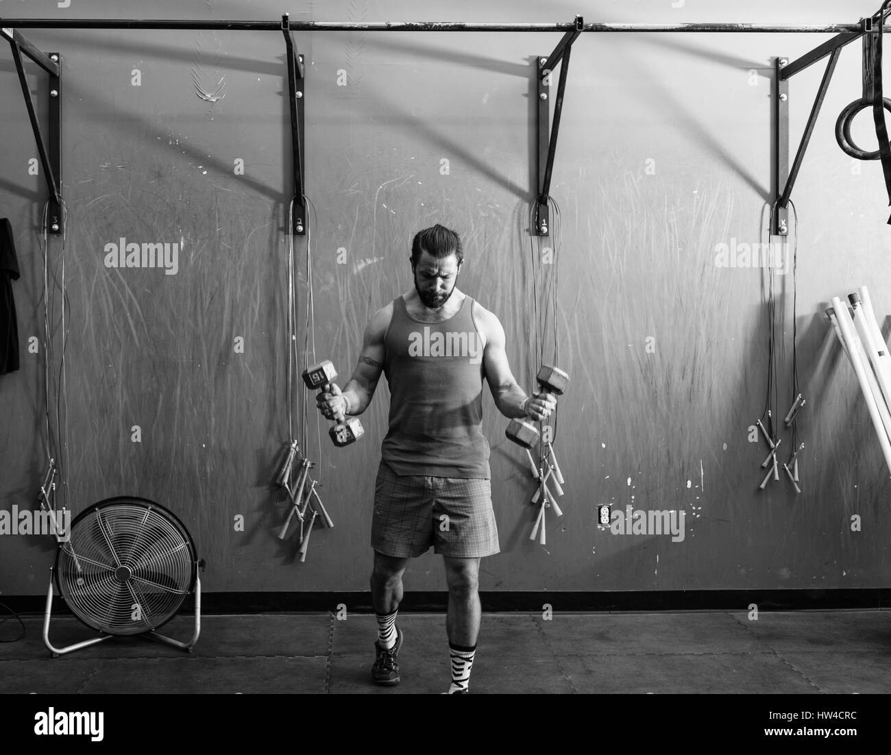 Mixed Race man lifting dumbbells in gymnasium Stock Photo