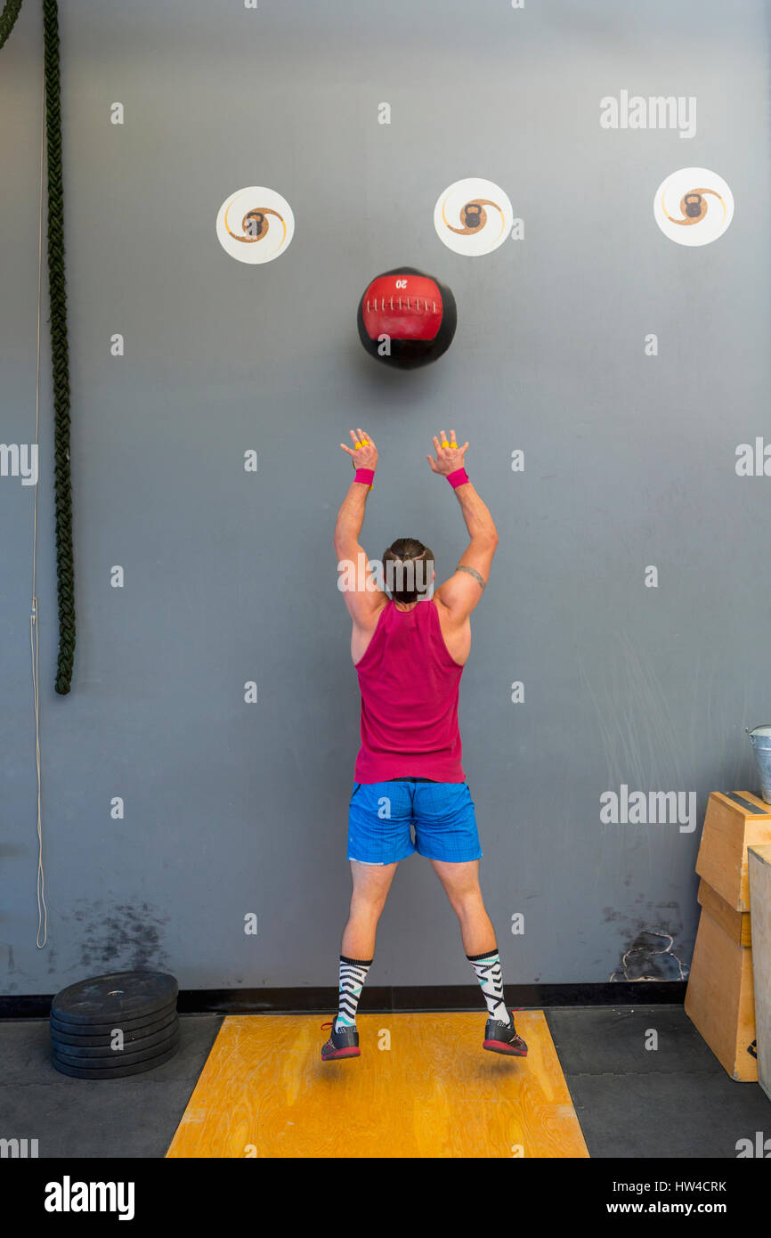 Mixed Race man throwing heavy ball against wall Stock Photo
