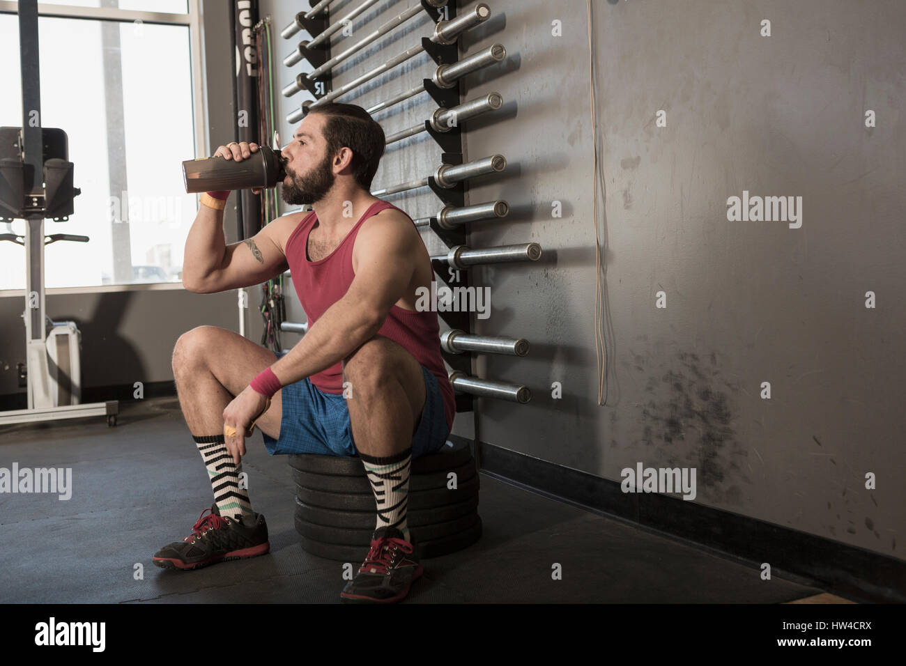 Mixed Race man drinking from bottle in gymnasium Stock Photo