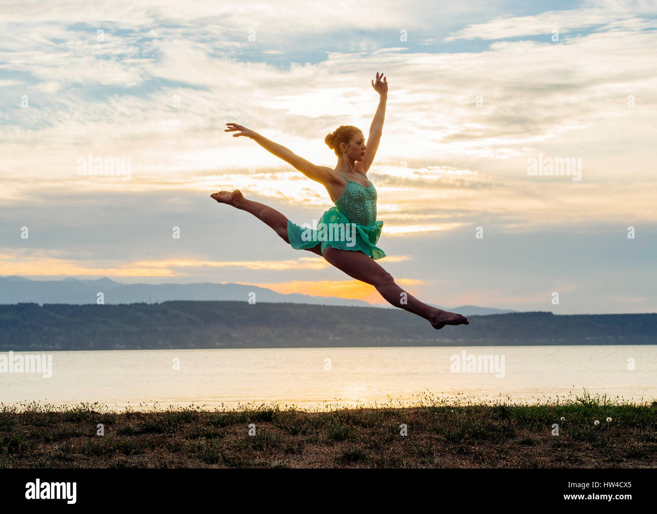 Caucasian ballerina jumping on beach Stock Photo