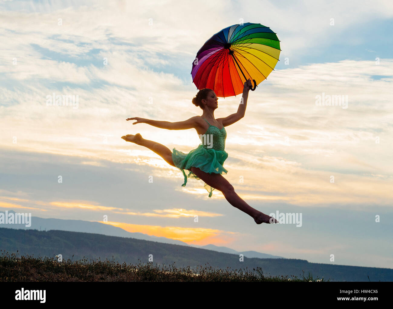 Caucasian ballerina jumping with multicolor umbrella Stock Photo