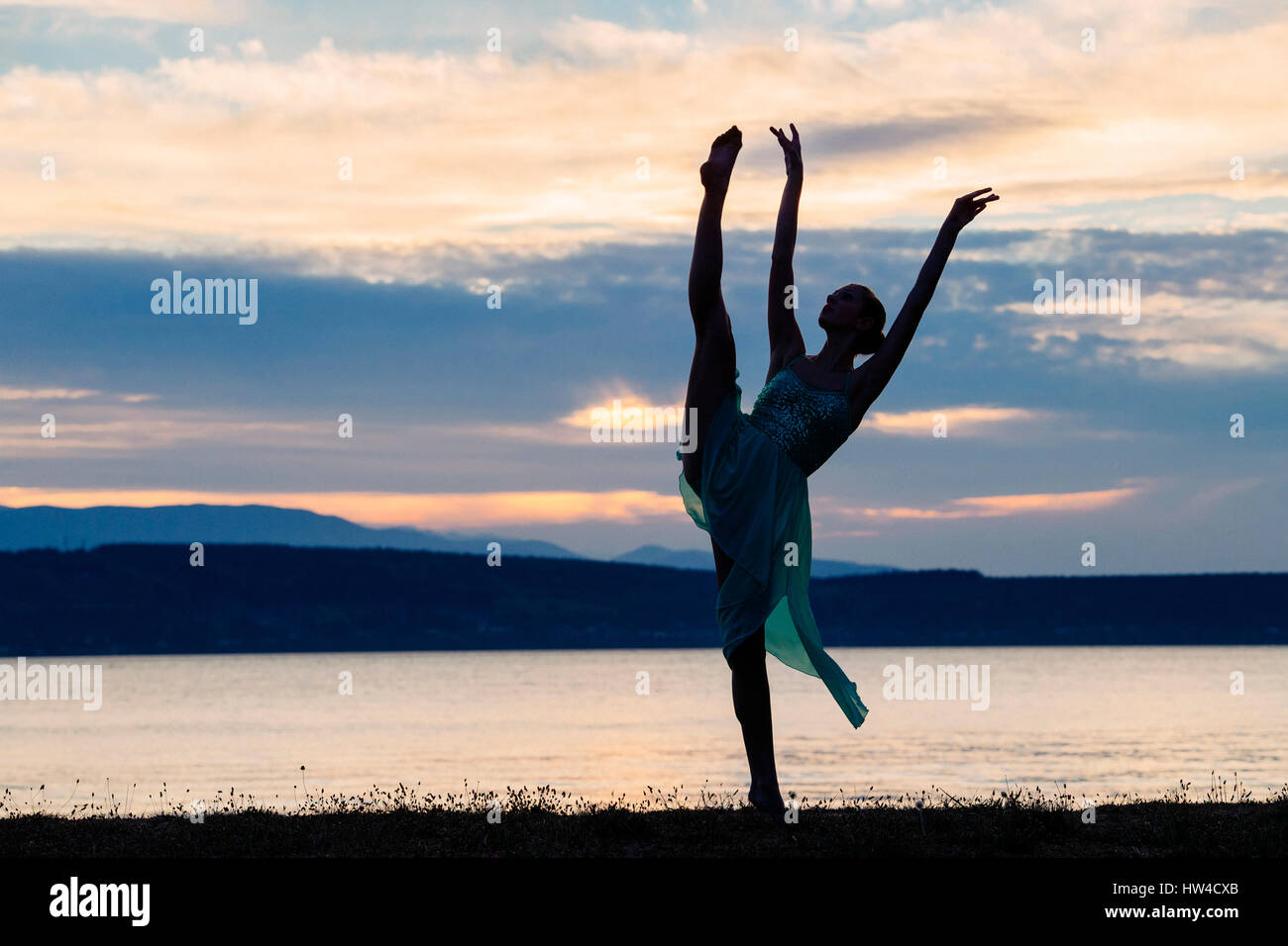 Caucasian ballerina dancing on beach at sunset Stock Photo