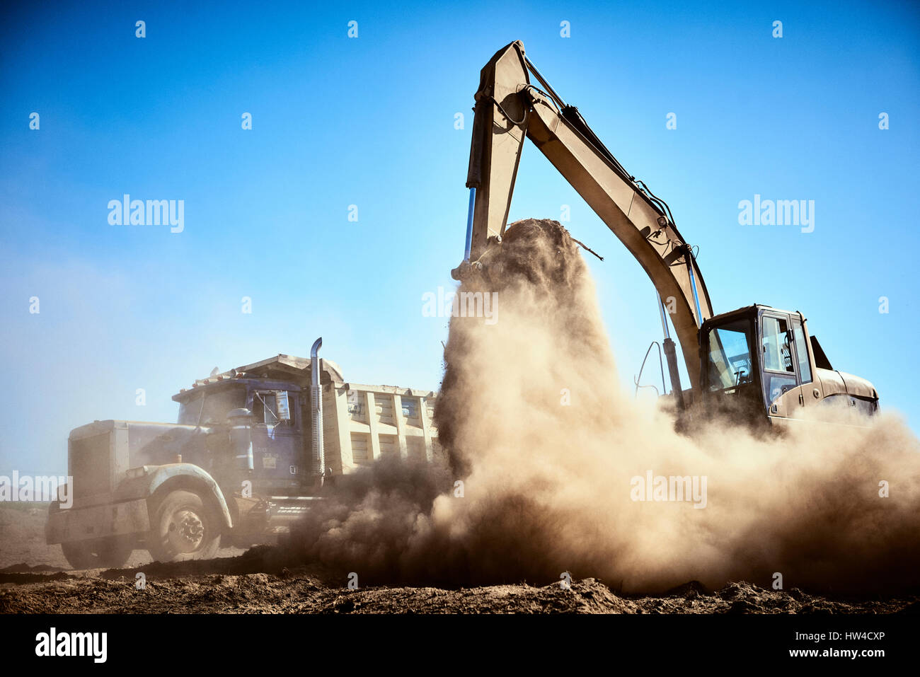 Truck near digger in dirt field Stock Photo