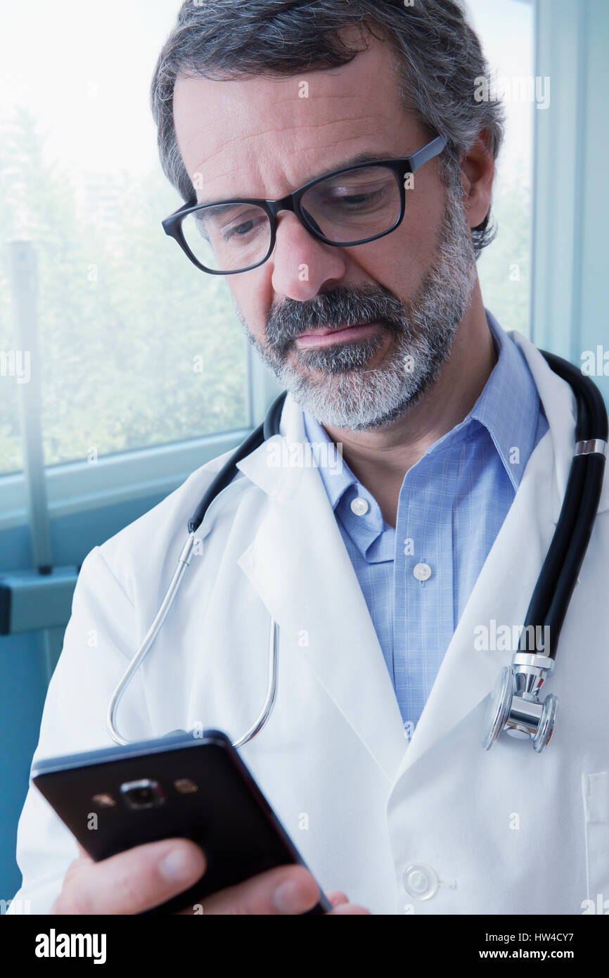 Hispanic doctor texting on cell phone Stock Photo