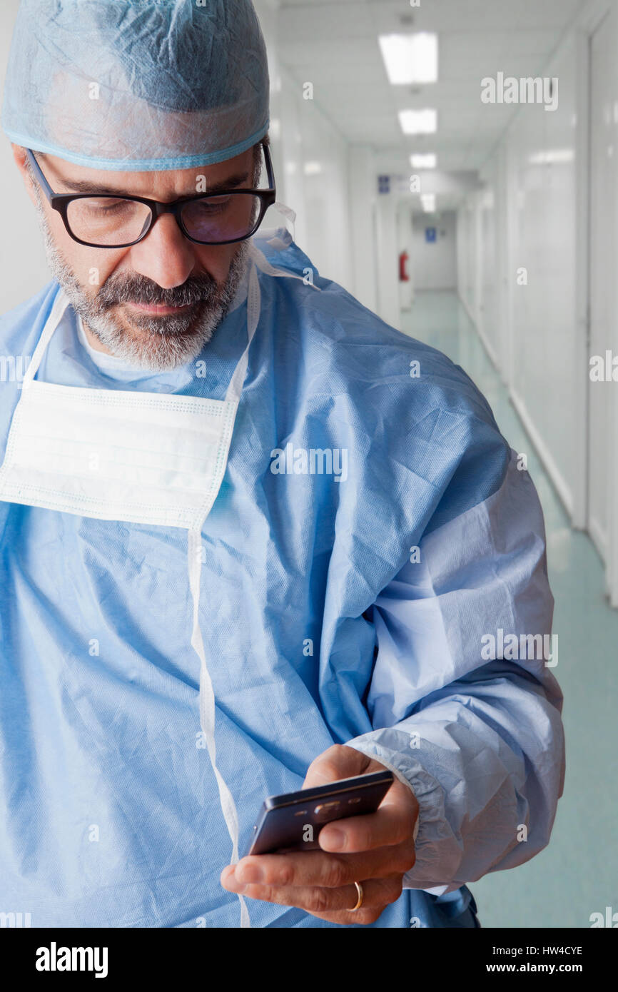 Hispanic surgeon texting on cell phone Stock Photo