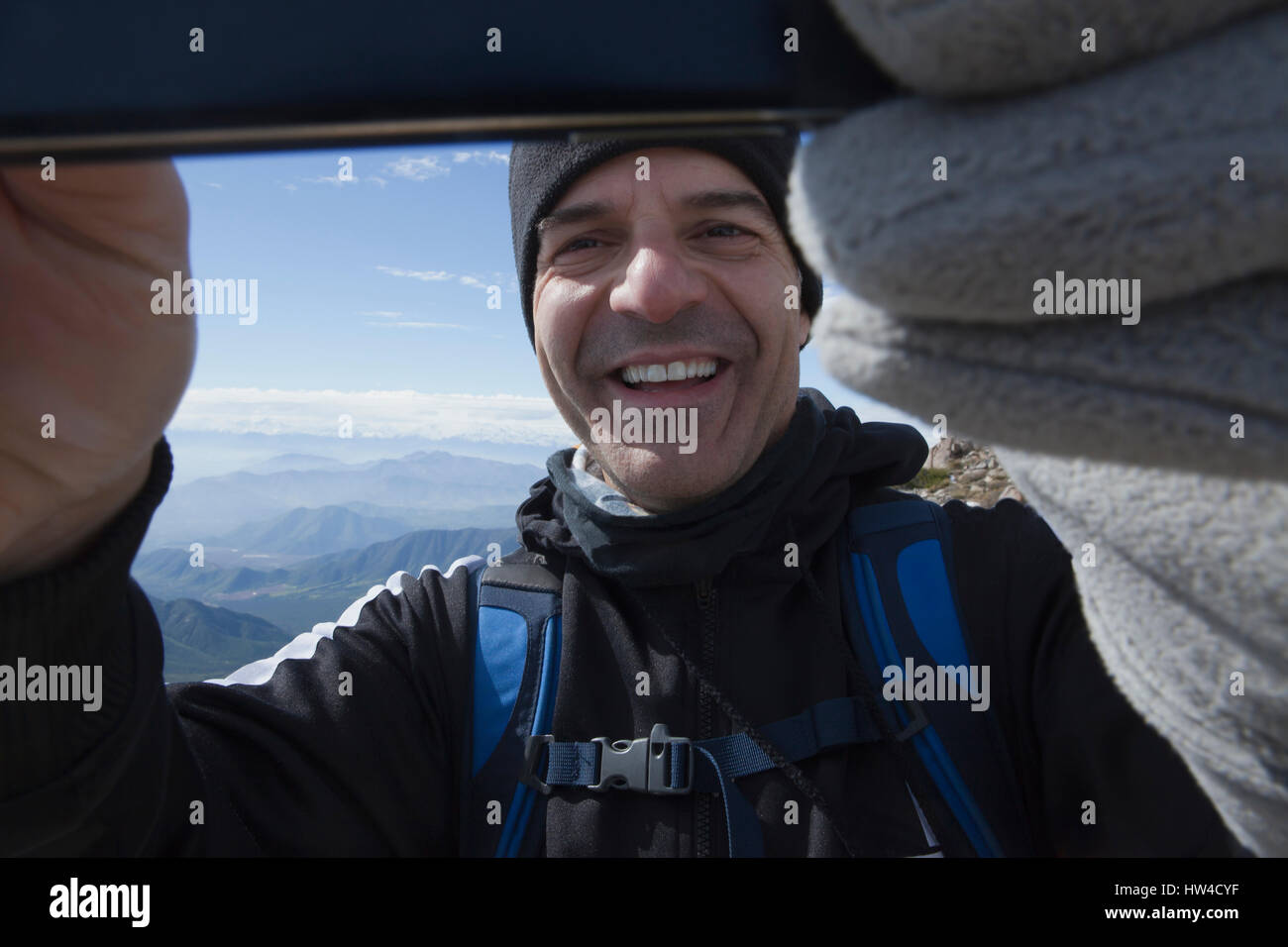Hispanic man posing for cell phone selfie on mountain Stock Photo