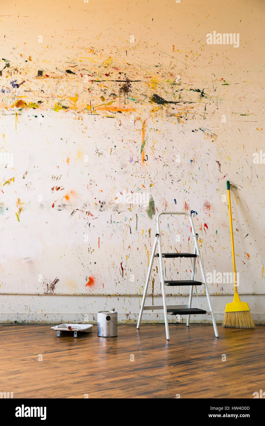 Paint splattered on wall near ladder and broom Stock Photo