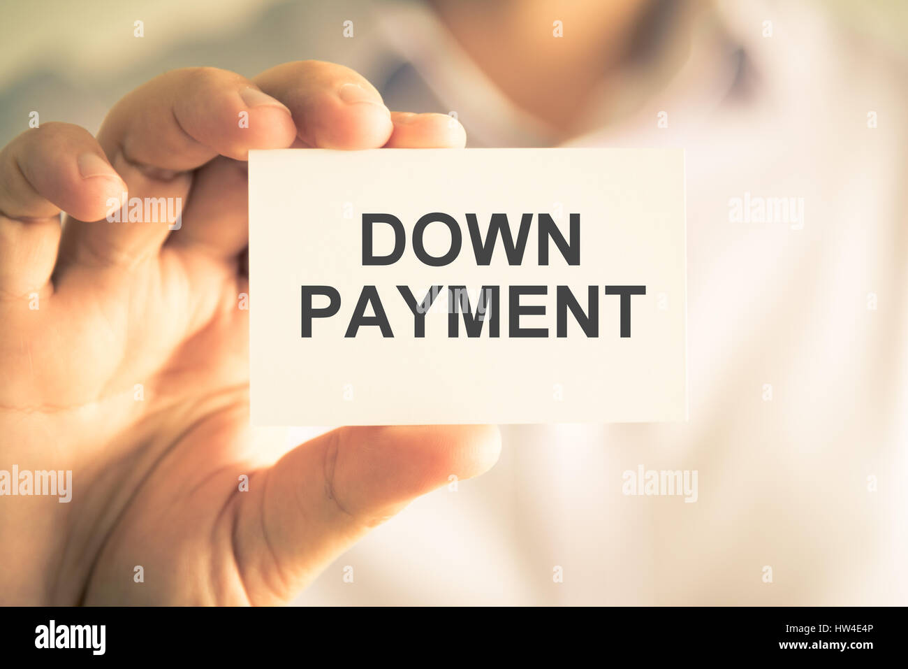 Closeup on businessman holding a card with text DOWN PAYMENT, business concept image with soft focus background and vintage tone Stock Photo