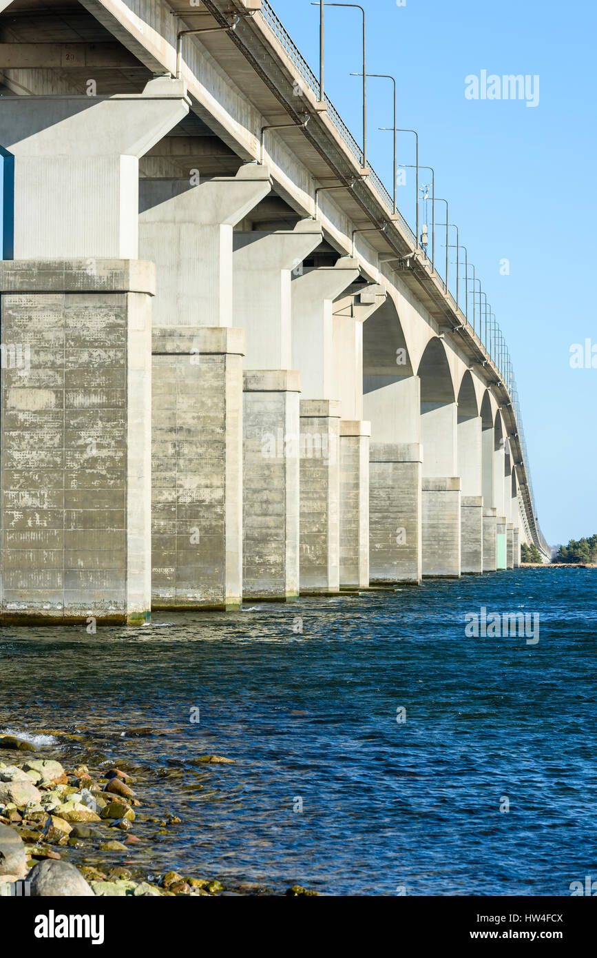 Concrete bridge over water. Gray pillars support the weight of the