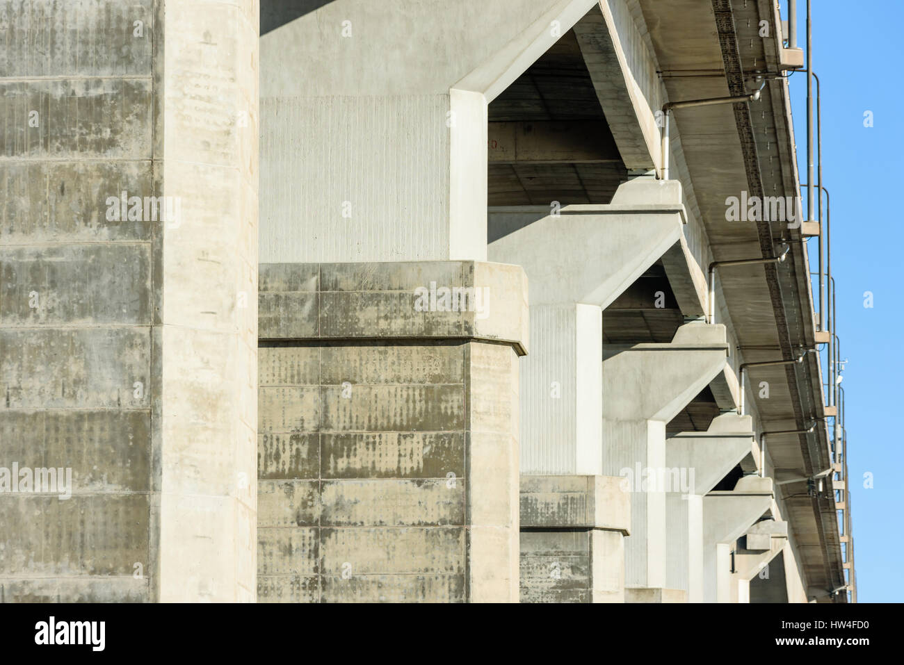Underside of viaduct with gray concrete pillars, drainpipes and protruding road. Stock Photo