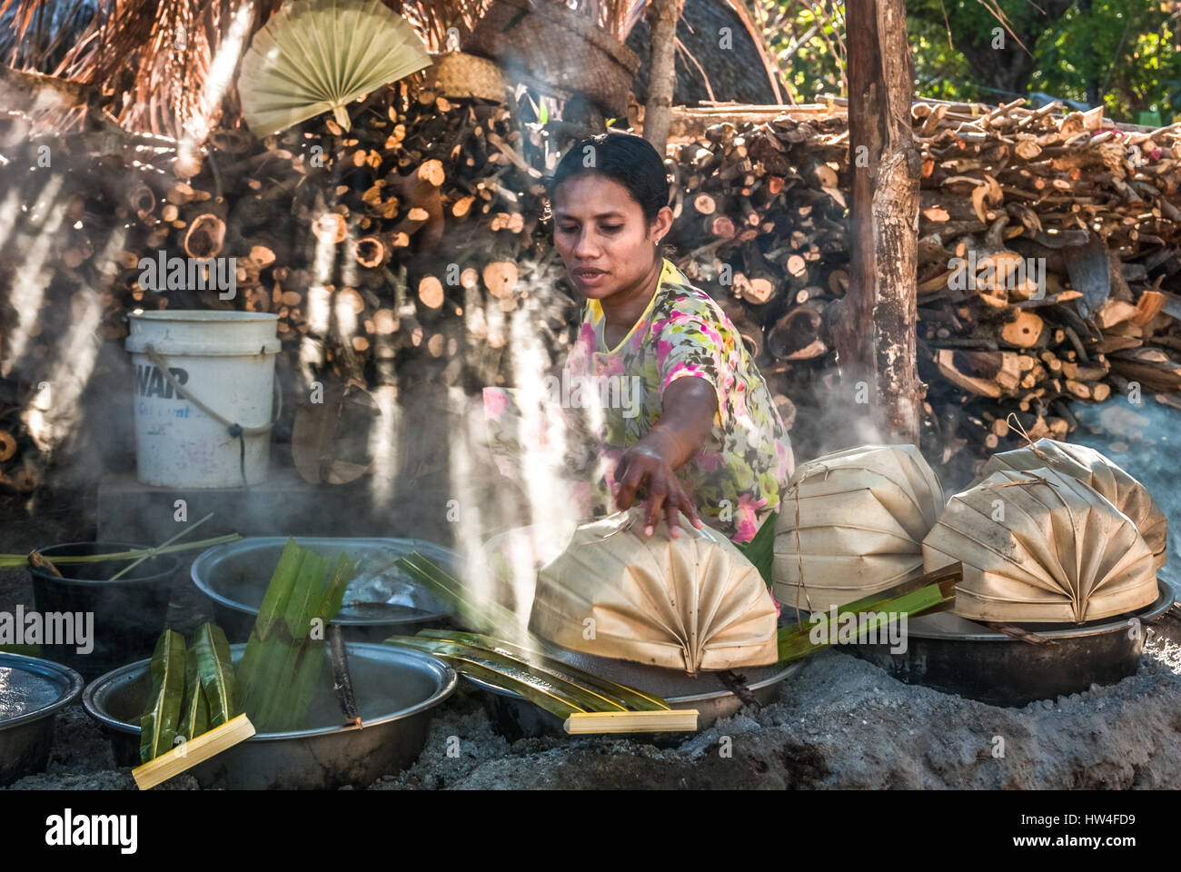 A woman boiling the sap of the Palmyra palm (Arenga pinnata) to produce palm sugar in Rote Island, Indonesia. Stock Photo