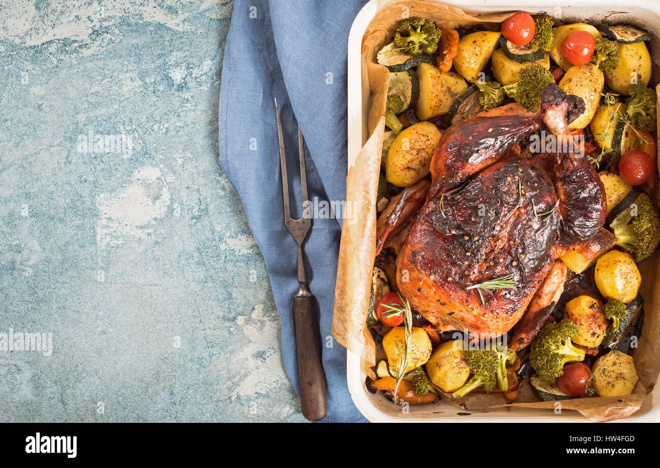 Whole grilled chicken with vegetables into roasting tray. Top view with