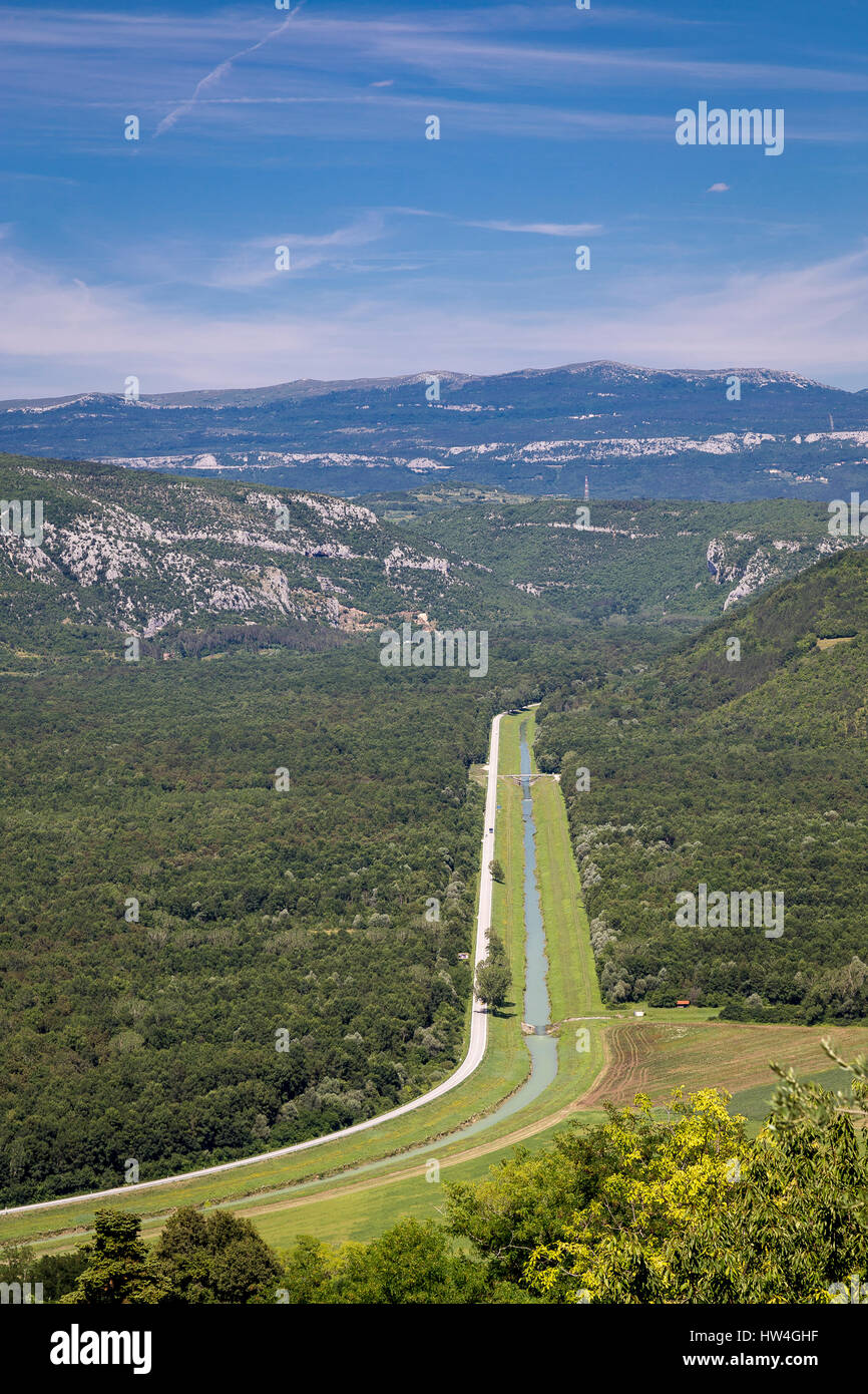 A long, straight valley road and water channel in the mountains of Istria, Croatia. Stock Photo