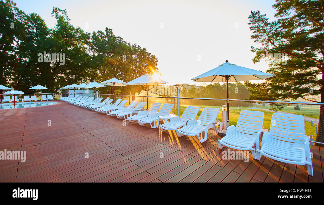 Relaxing chairs beside swimming pool. Summer morning Stock Photo Alamy