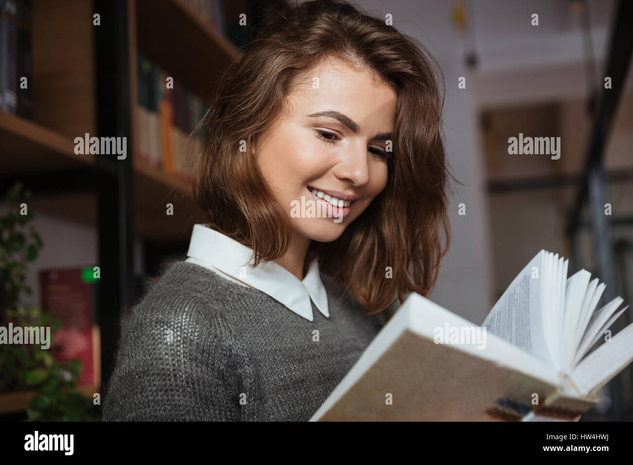 Close up of a smiling student girl reading book in library Stock Photo ...