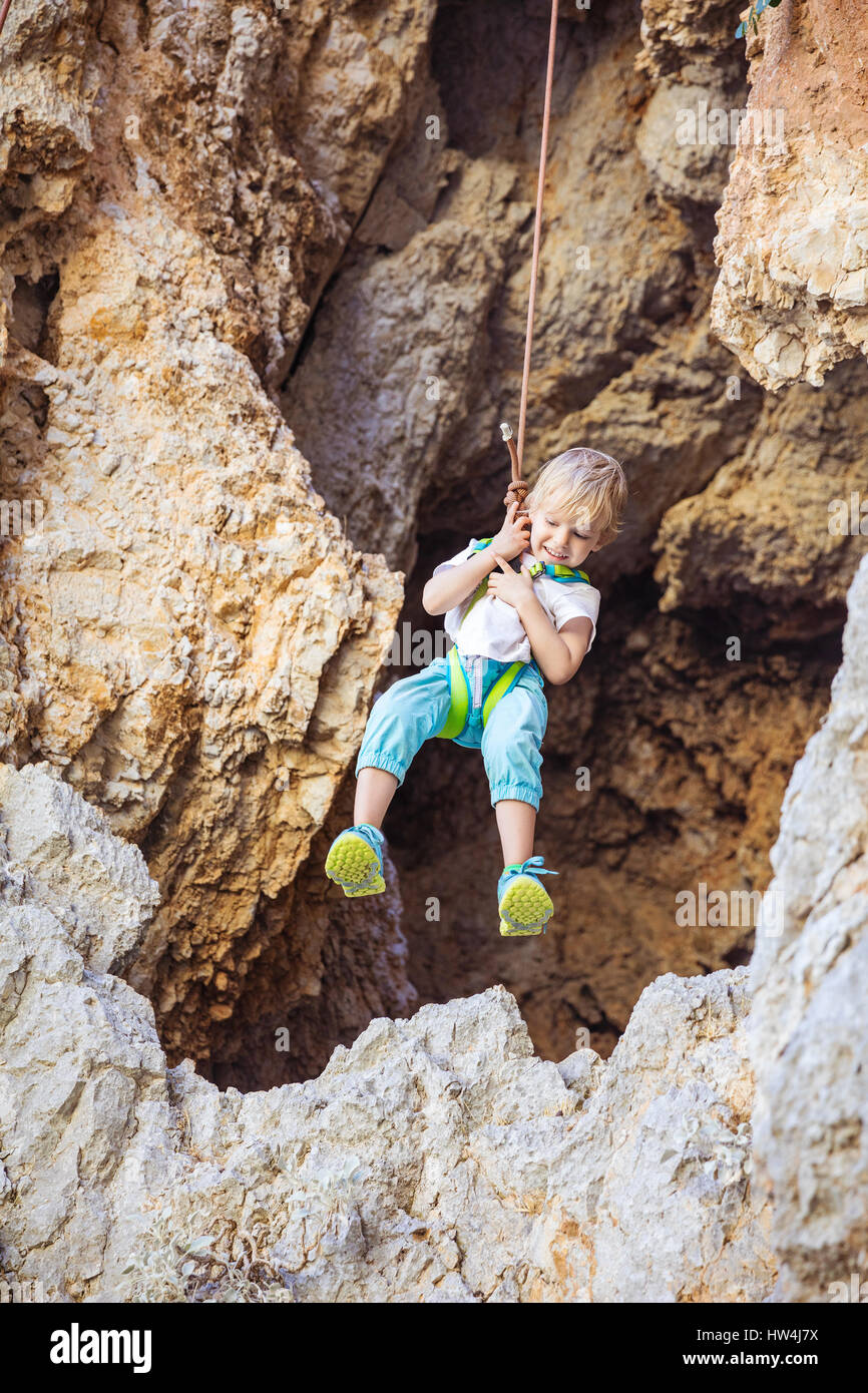 Little boy being lowered down while top rope climbing and smiling Stock ...