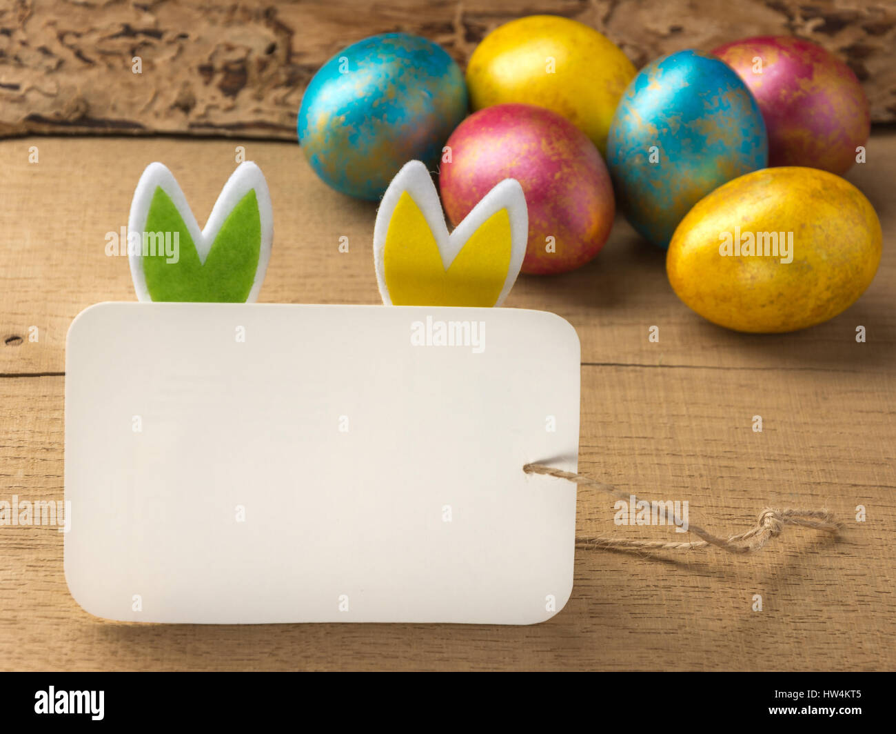 Multi-colored easter eggs on a natural wooden background. Copy space. Stock Photo