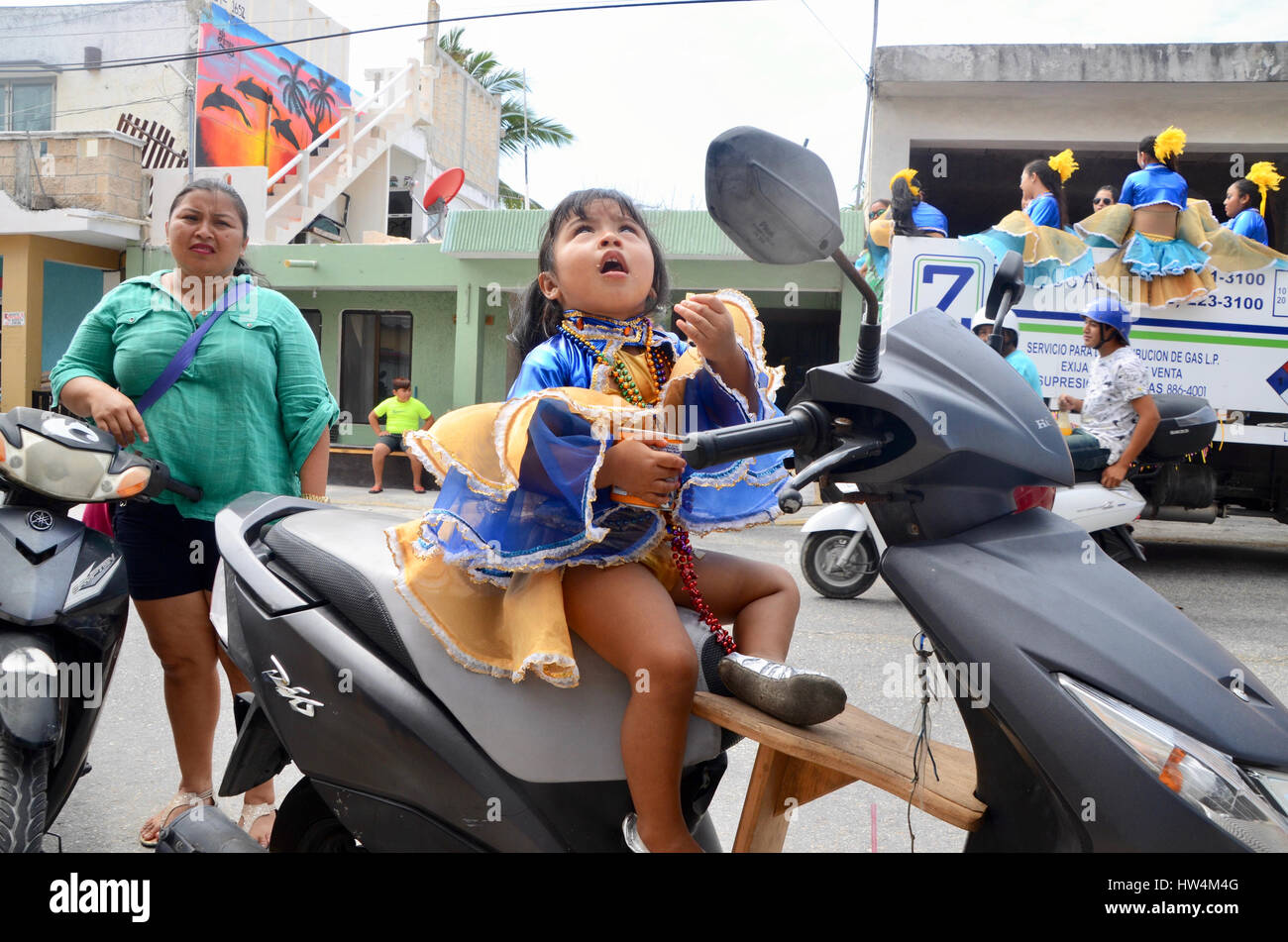 little girl carnival goer sits on scooter moped eating crisps chips