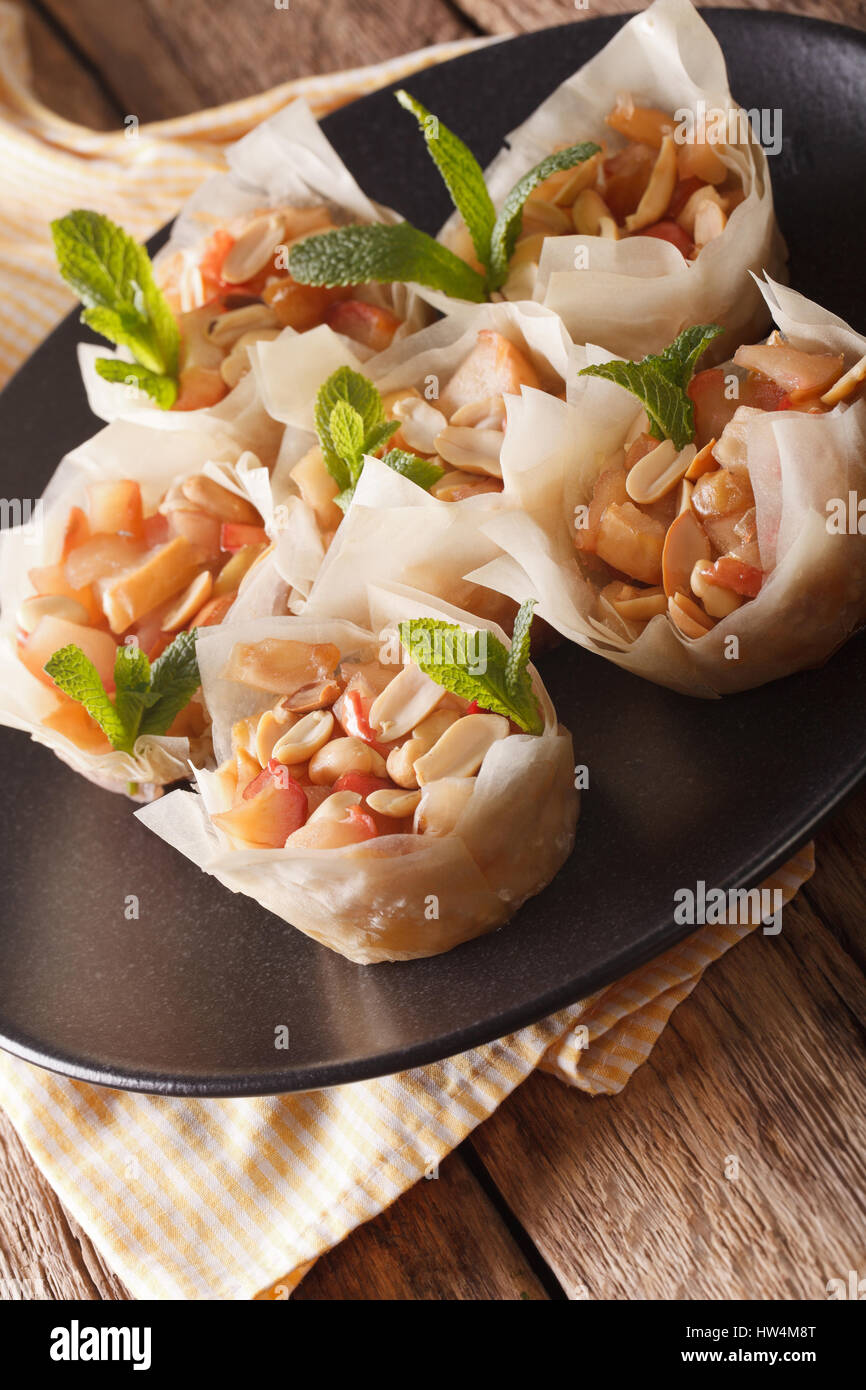 Cups of dough filo stuffed with apples and peanuts close-up on a plate. vertical Stock Photo