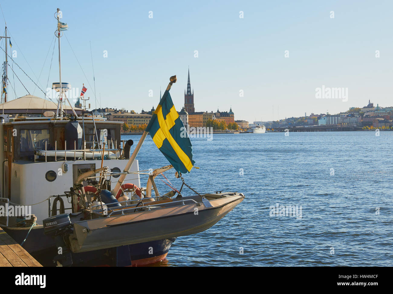 Swedish flag on boat on Kungsholmen waterfront with Riddarholmskyrkan in the background, Stockholm, Sweden, Scandinavia. Stock Photo