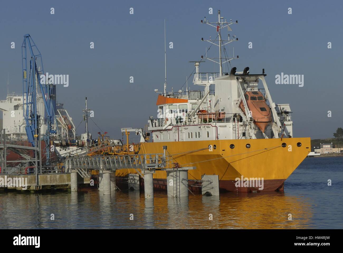 Products Tanker discharging at the Oil Terminal of Lorient, France, with yellow  hull and white funnel on a sunny day. Stock Photo
