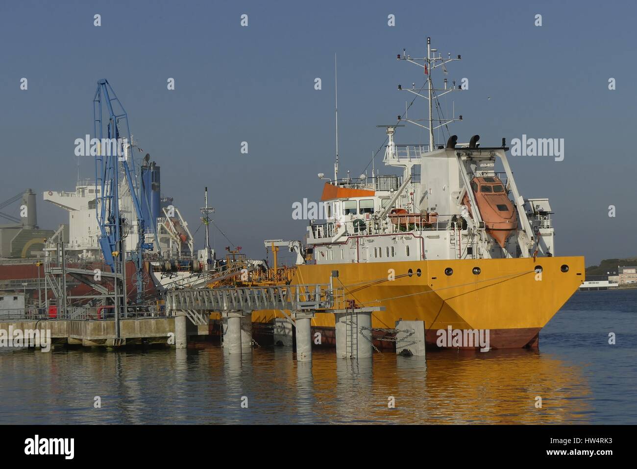 Products Tanker discharging at the Oil Terminal of Lorient, France, with yellow  hull and white funnel on a sunny day. Stock Photo