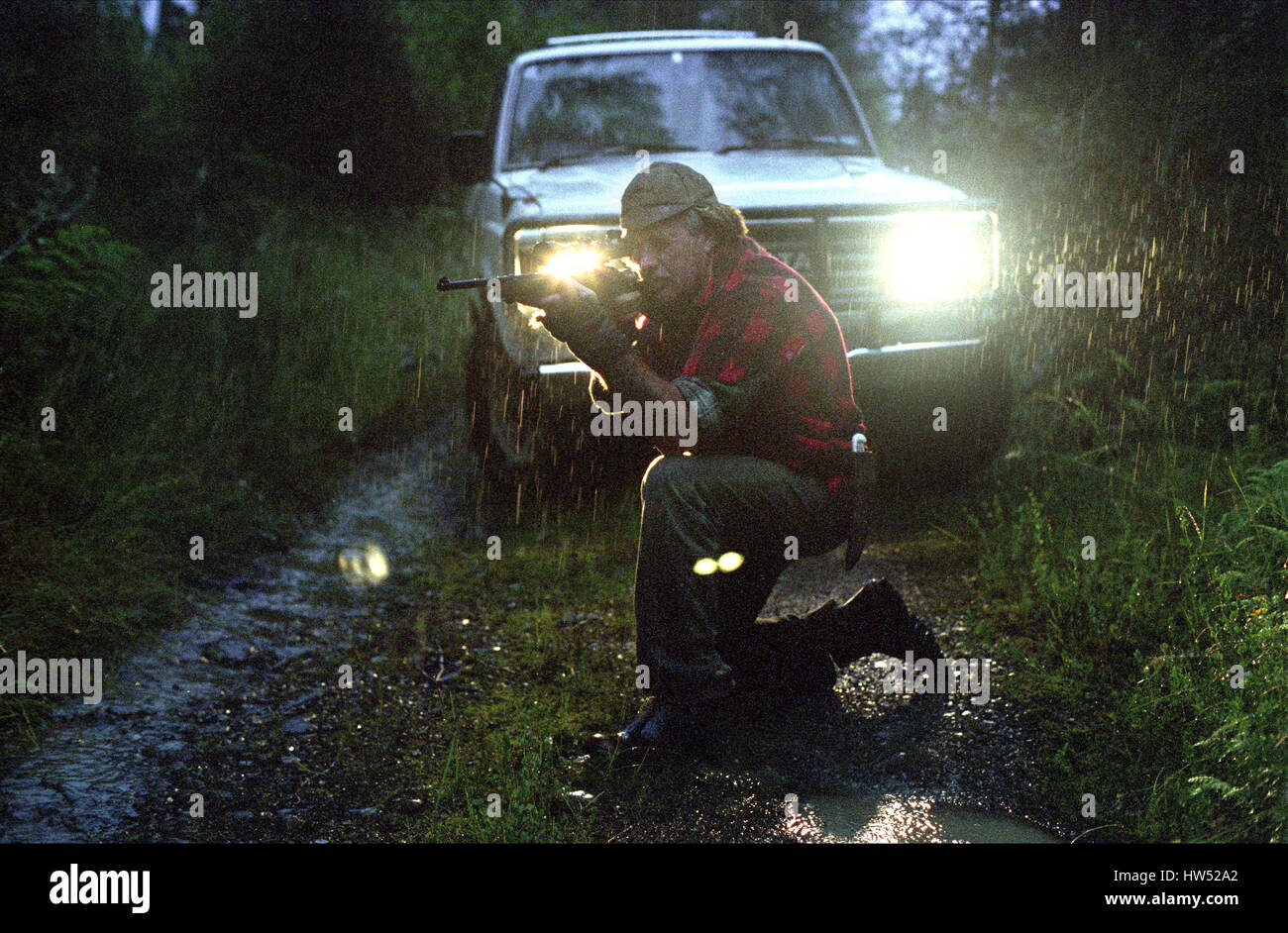 A man is kneeling down hunting for Possum, New Zealand, South Island. Stock Photo