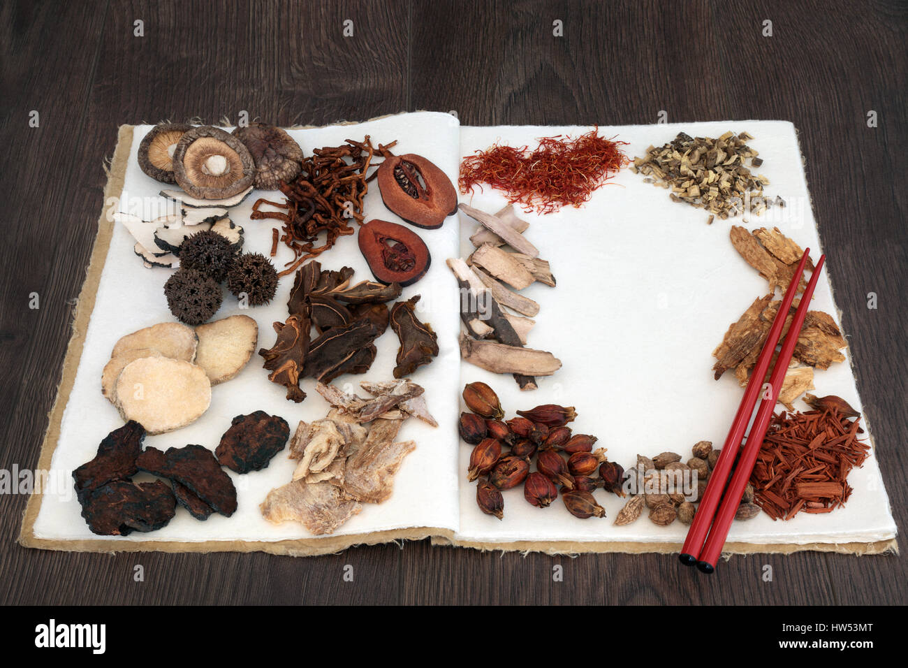 Chinese herb selection used in traditional herbal medicine with chopsticks on a hemp notebook  on oak background. Stock Photo