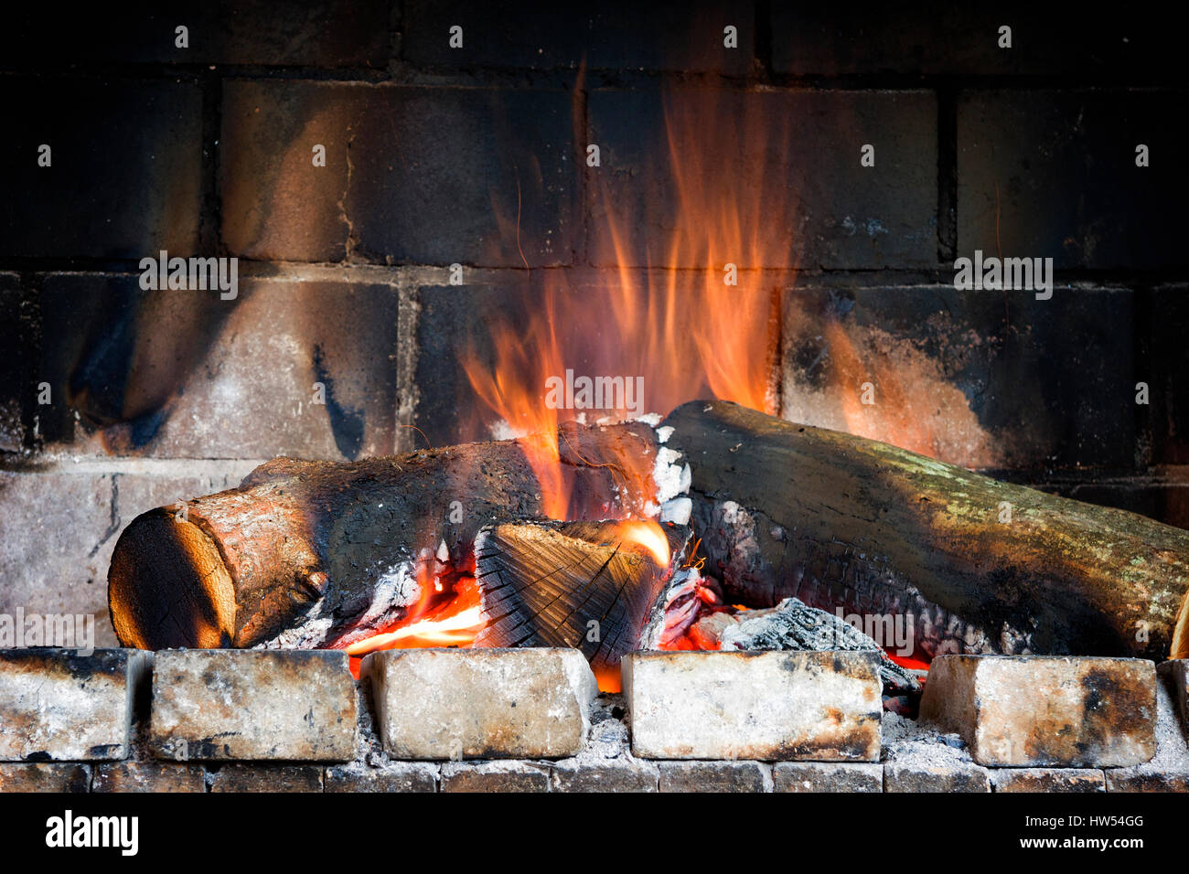 Flaming log fire in a traditional brick fireplace Stock Photo