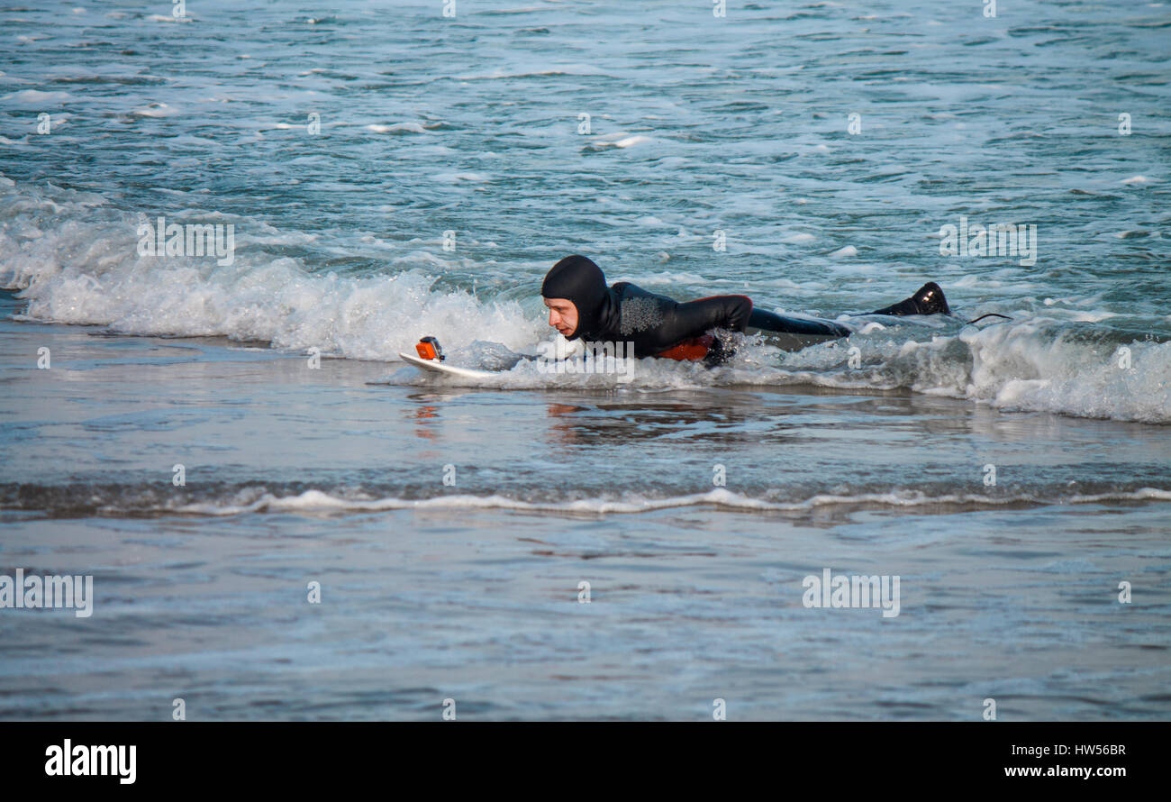 Surfer is shooting himself in the water with surfboard. Selfie in water Stock Photo