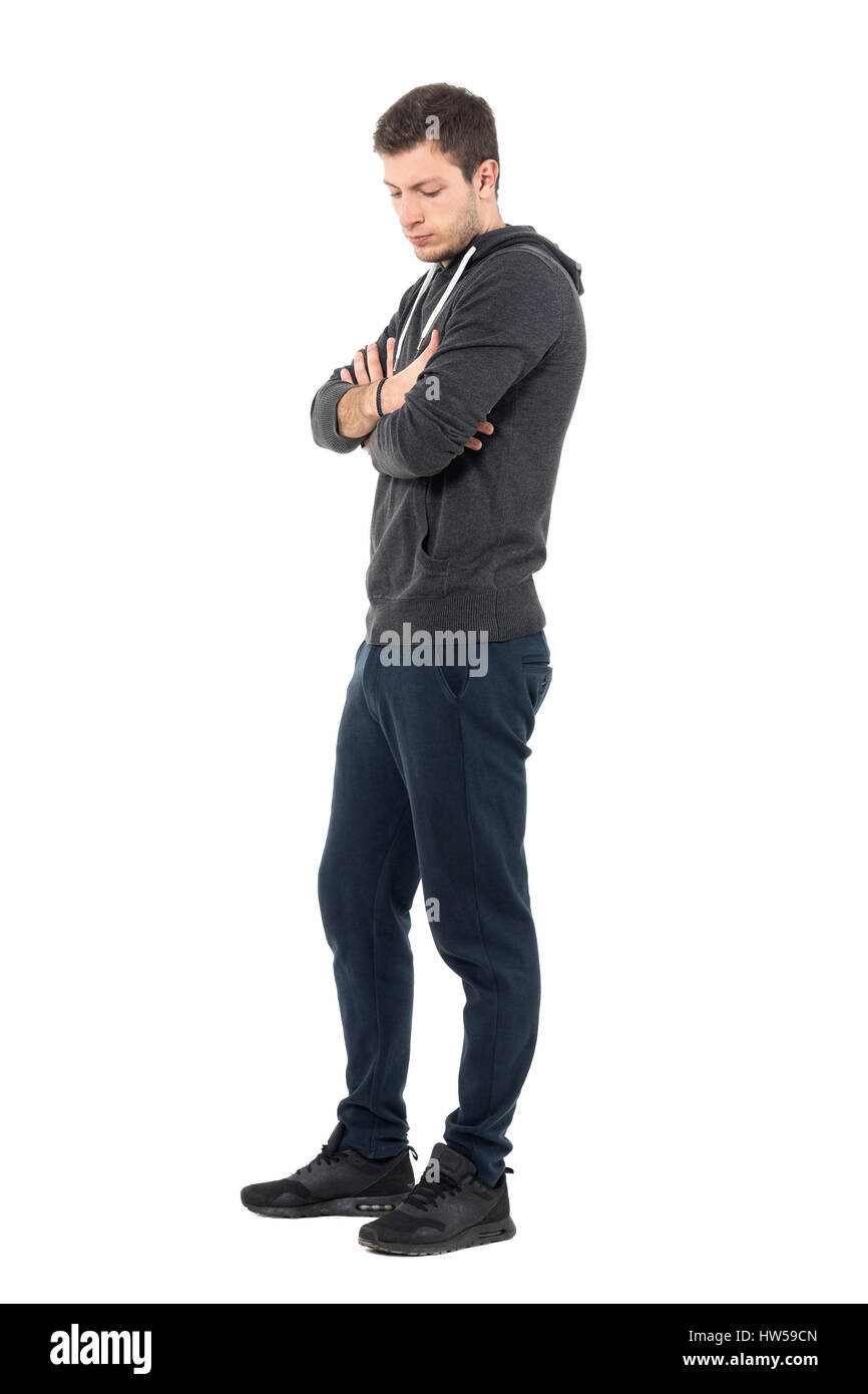 Side view of sad young man in sportive clothing looking down with crossed  arms. Full body length portrait over white studio background Stock Photo -  Alamy
