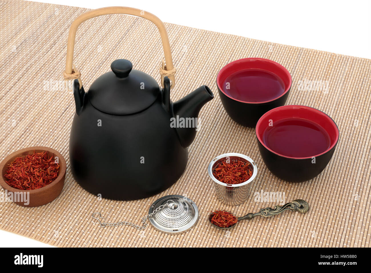 Safflower herb tea with oriental teapot and cups with strainer and old