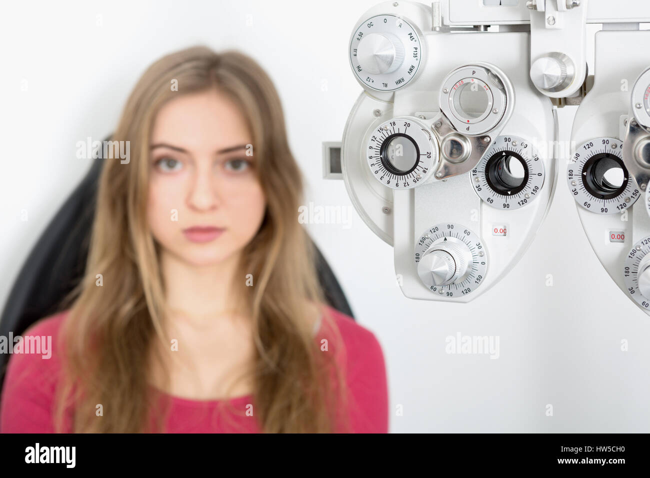 woman patient waiting for eye examination with phoropter at optometrist clinic - sharpness on phoropter Stock Photo