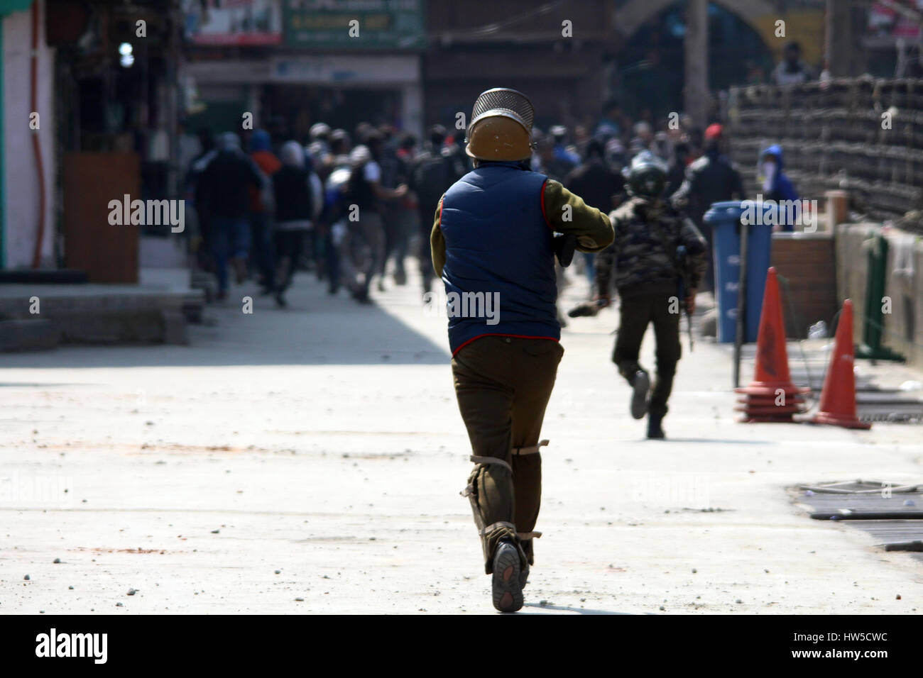 Srinagar, Kashmir. 17th Mar, 2017. A policeman chasing the stone-pelters to fire tear gas canisters to disperse them in old city Srinagar on Friday, Kashmir. Credit: Umer Asif/Pacific Press/Alamy Live News Stock Photo