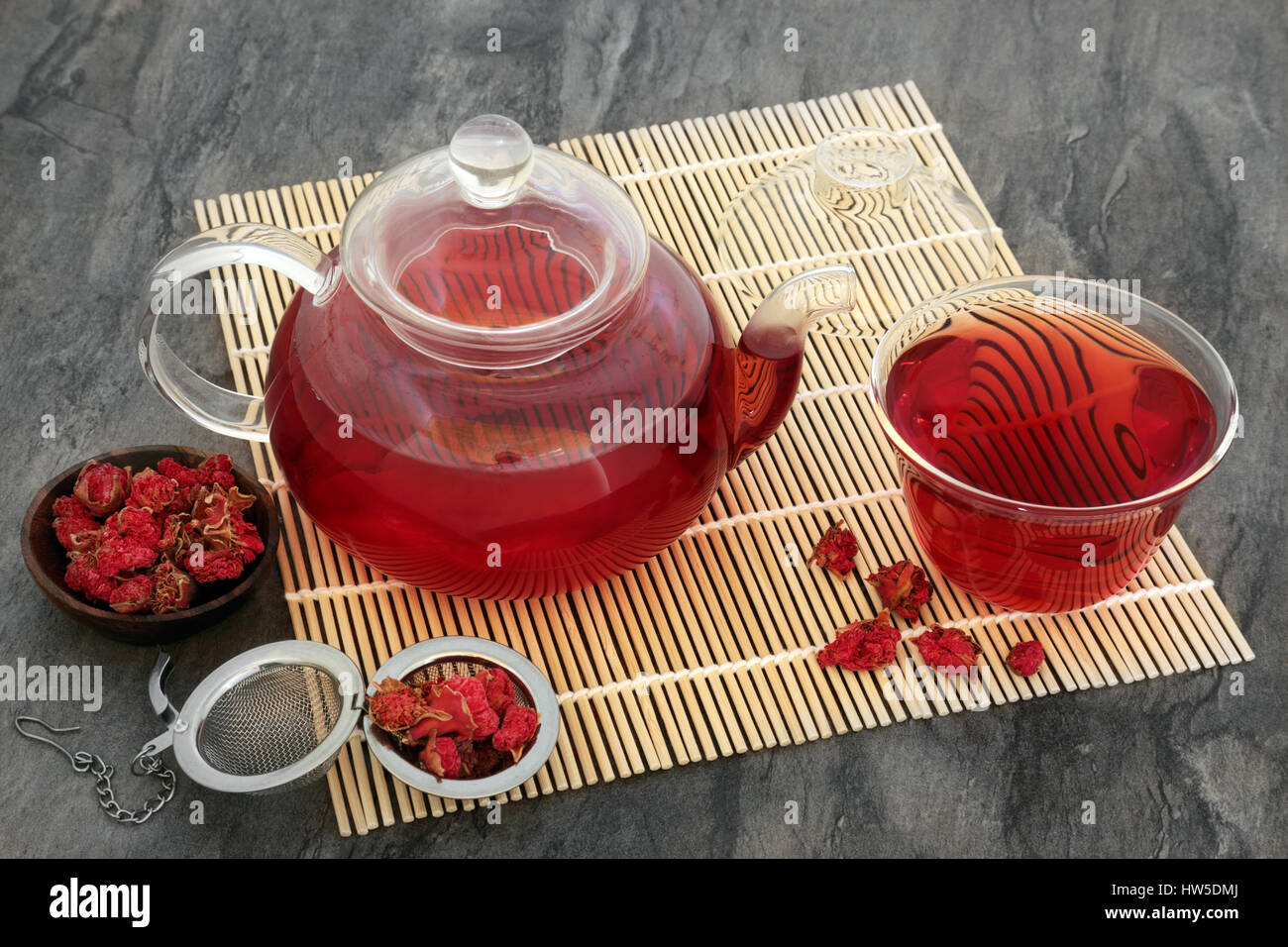 Pomegranate herb flower tea in glass teapot and cup with strainer on bamboo mat Stock Photo Alamy