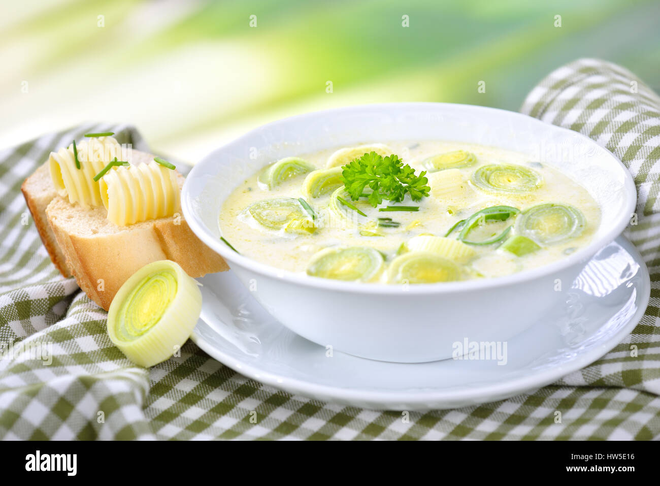 Creamy vegetarian cheese and leek soup with buttered baguette, leeks in