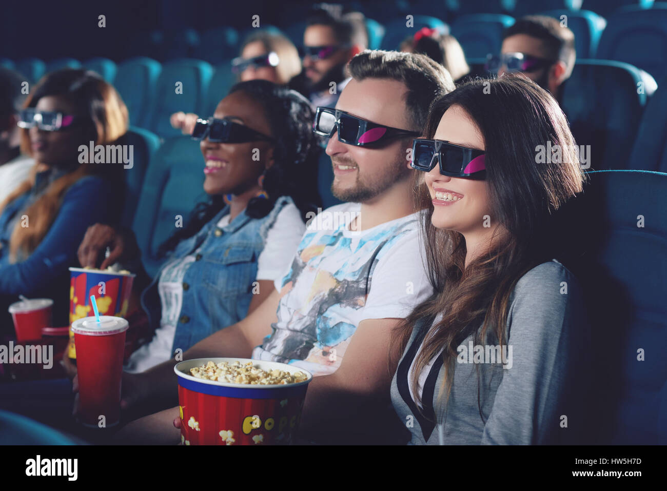 Friends  watching movie in cinema and smiling together. Stock Photo