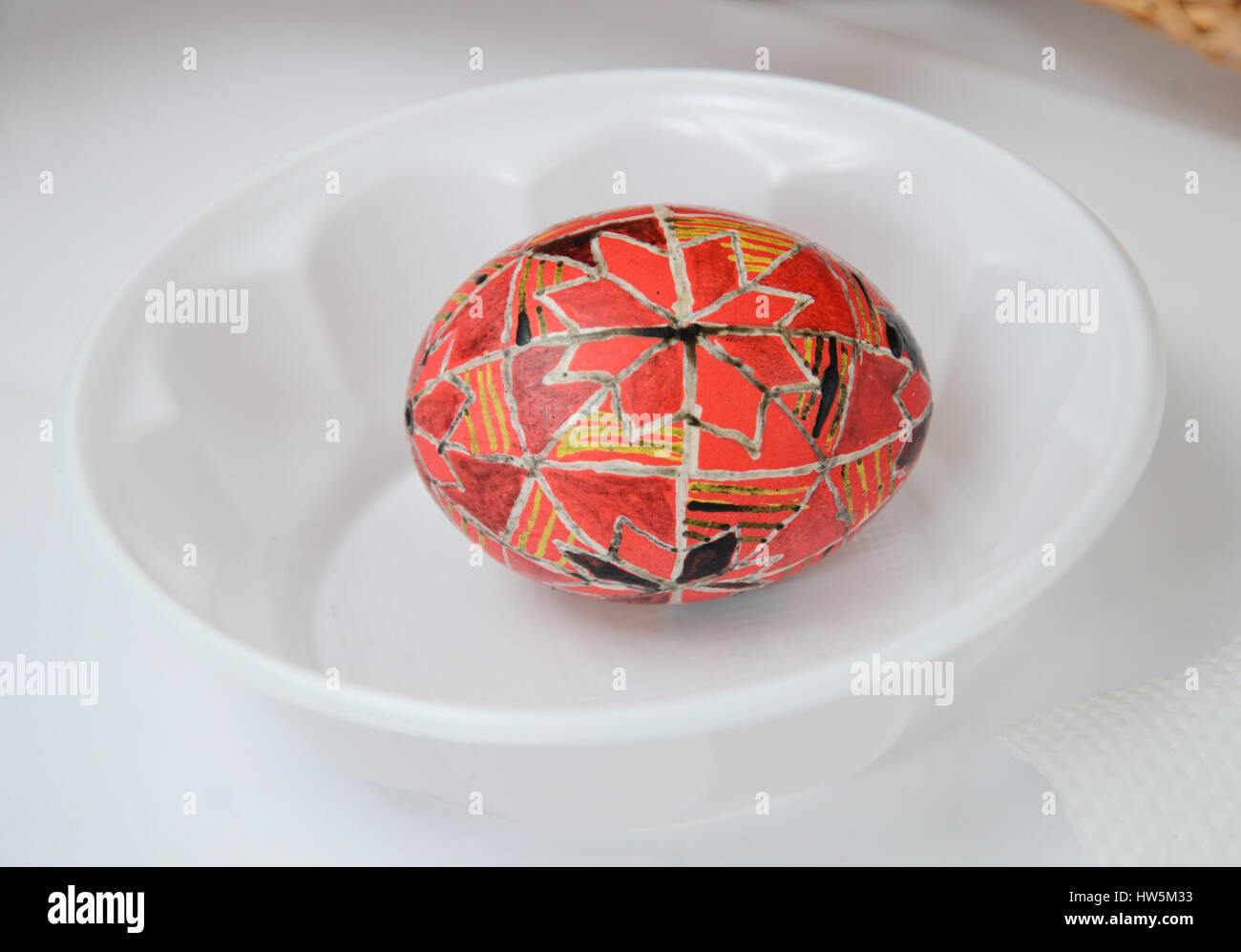 An Easter egg is decorated with traditional Ukrainian folk ornament using a wax-resist method. The pysanka is covered with wax and dyed red and yellow Stock Photo