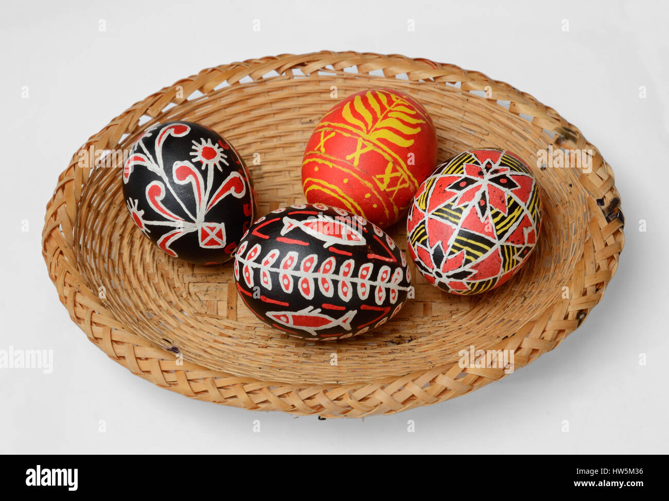 The bunch of handmade pysankas are gathered inside of the straw basket. The Easter eggs are decorated with a pattern using a wax-resist method. Stock Photo