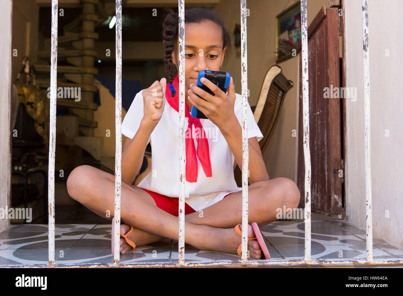 Cuba, Sancti Spiritus Province, Trinidad de Cuba listed as World Heritage by UNESCO, young girl in school uniform playing video game Stock Photo