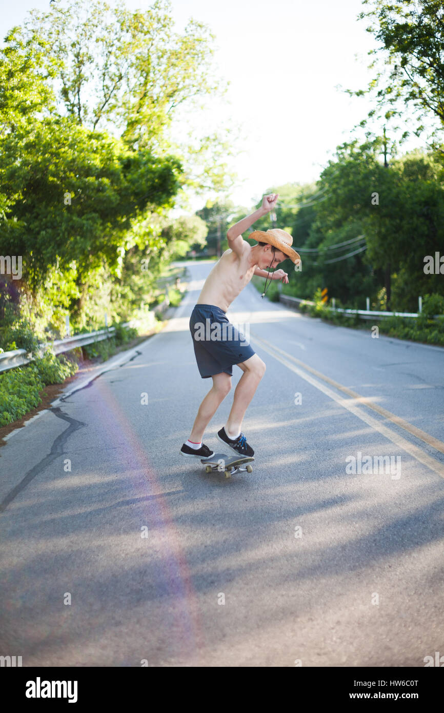 Boy skateboarding down the road Stock Photo