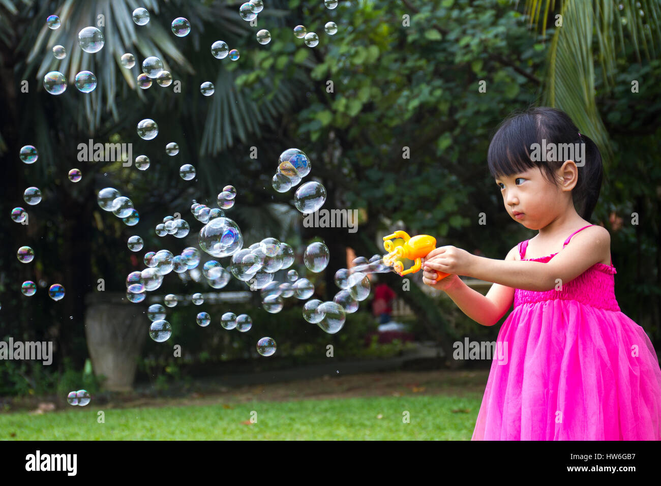 Asian Little Chinese Girls Shooting Bubbles from Bubble Blower in the Park Stock Photo