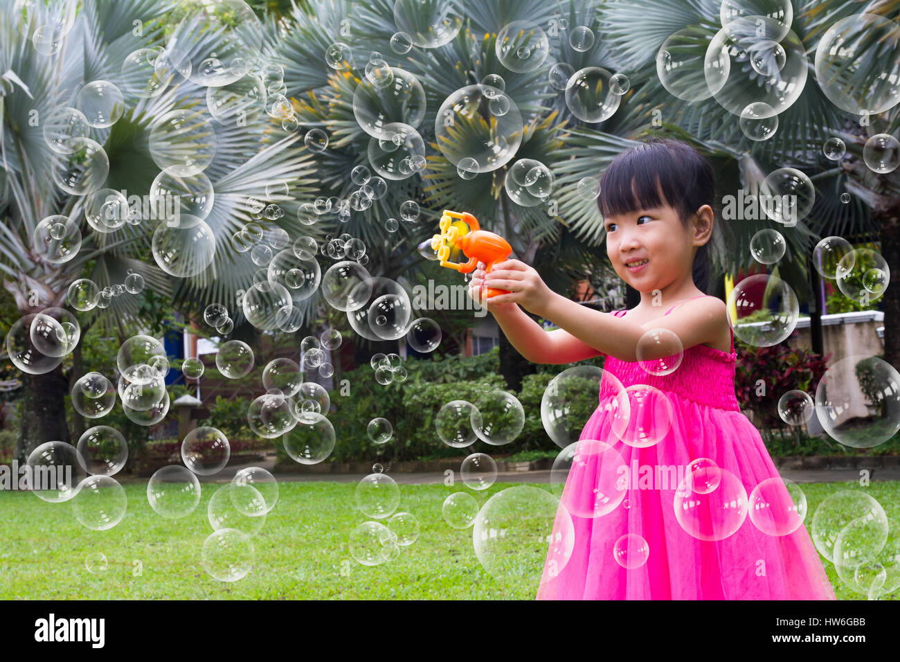 Asian Little Chinese Girls Shooting Bubbles from Bubble Blower in the Park Stock Photo