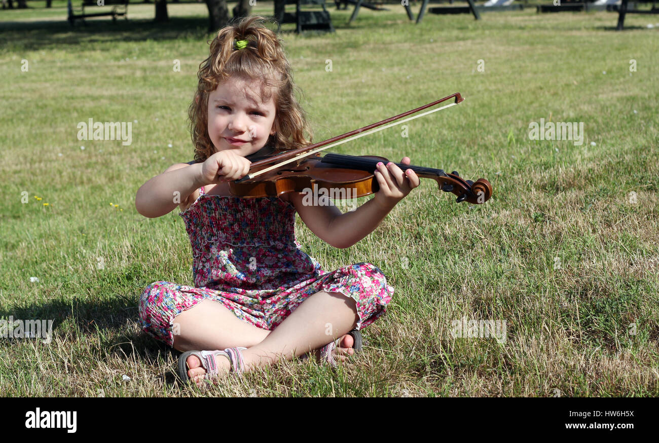 little girl sitting on grass and play violin Stock Photo - Alamy