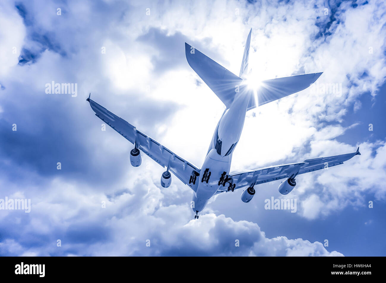 abstract of a large passenger jet landing through blue toned clouds Stock Photo