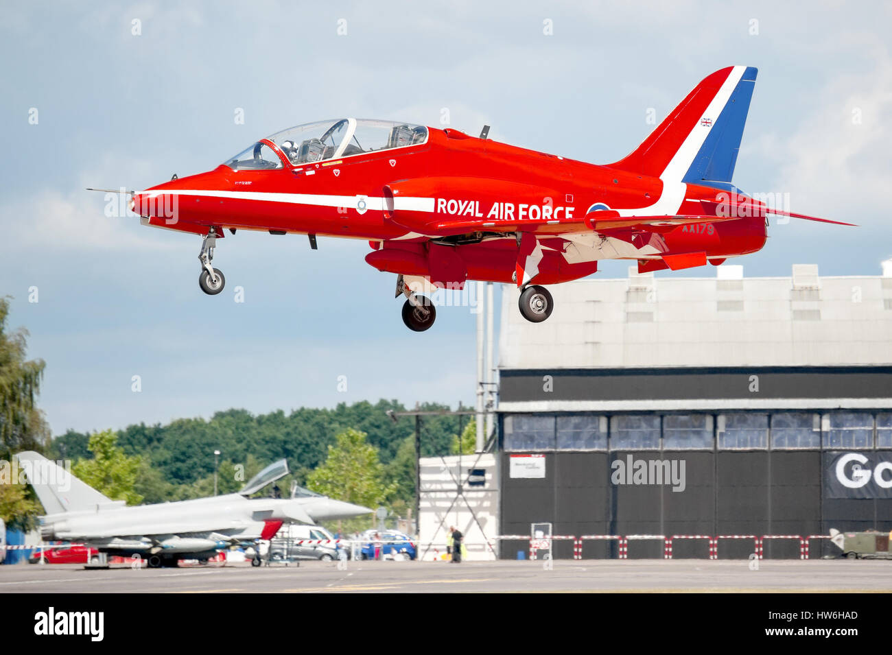 Close-up of a Red Arrows display jet landing with a Eurofighter in the background at the Farnborough Airshow, UK Stock Photo