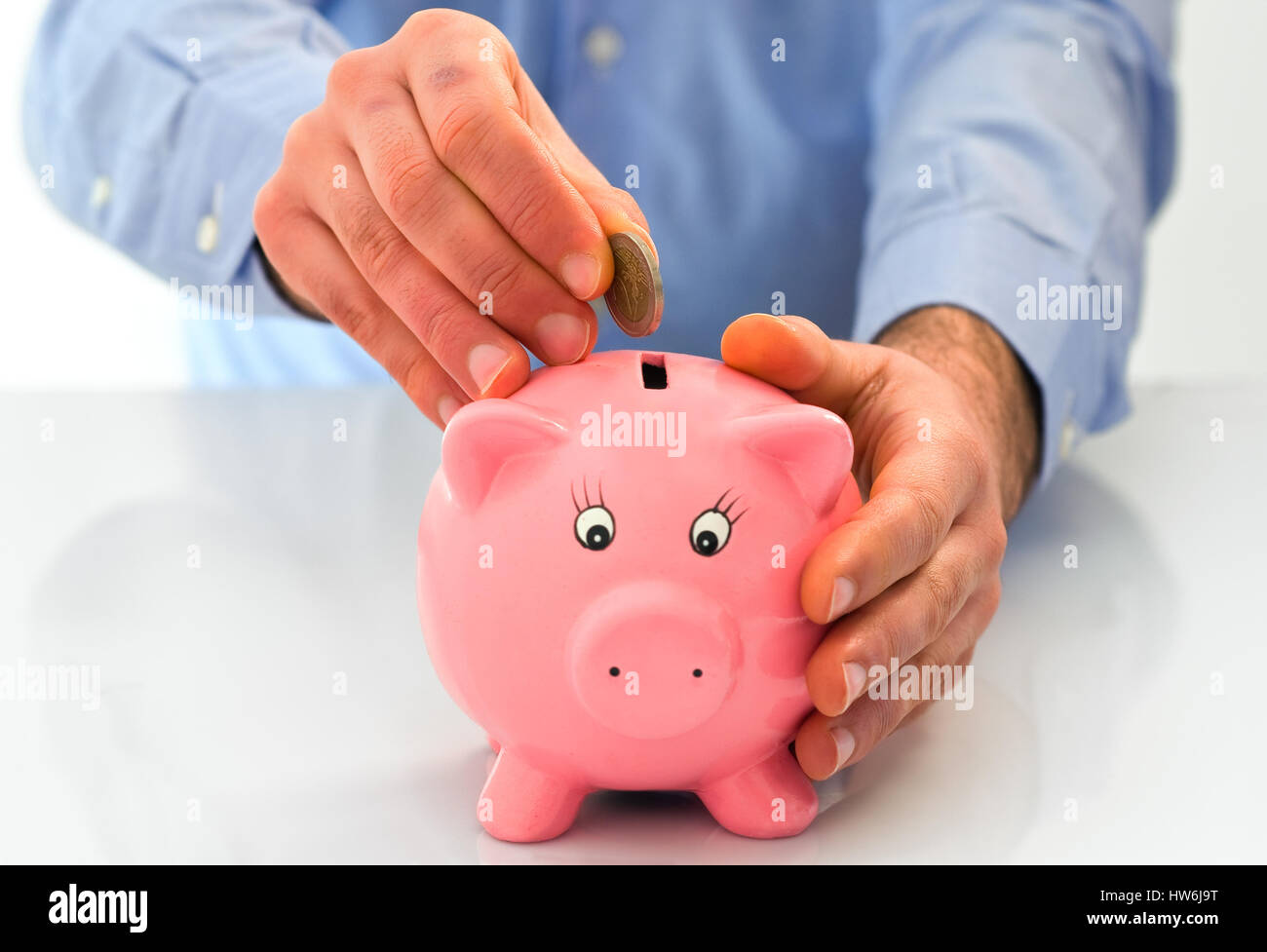 Man putting coin into a piggy bank Stock Photo - Alamy